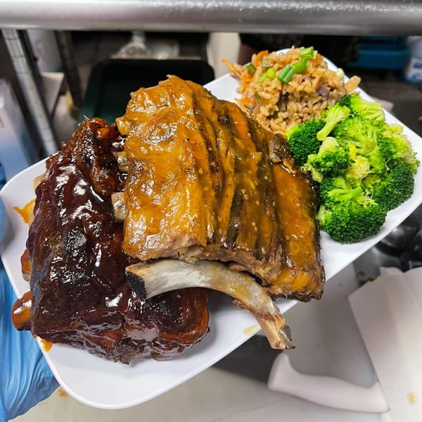 Two racks of ribs, one dark and one light, with rice and broccoli on a white plate.