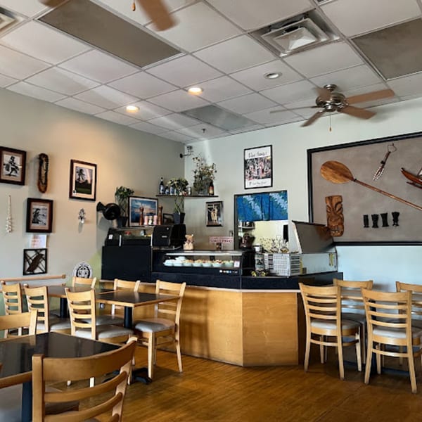Interior of Papa Nalu Aloha Grill with tables, chairs, a counter, and Hawaiian-themed decor.