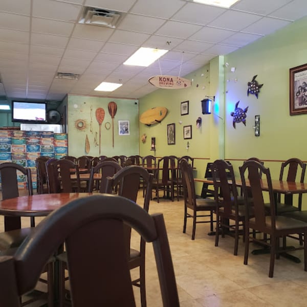 Interior of Papa Nalu Aloha Grill with tables, chairs, and Hawaiian-themed decor on light green walls.